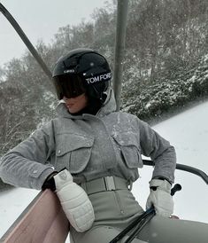 a woman in ski gear is sitting on a chair lift