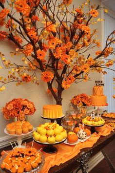 a table topped with lots of desserts next to a tree filled with orange flowers