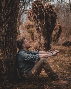 a man sitting under a tree in the woods