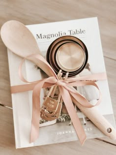 wooden spoons and utensils tied together on top of a magazine with pink ribbon