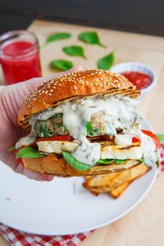 a hand holding a sandwich on top of a white plate