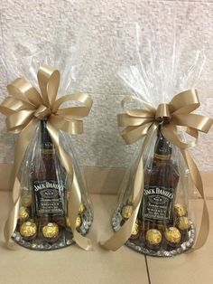 two wine bottles wrapped in plastic and tied with gold ribbon