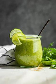 a green smoothie in a mason jar with a lime slice and cilantro