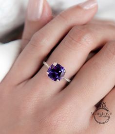 a woman's hand wearing a ring with an amethoraite stone in it