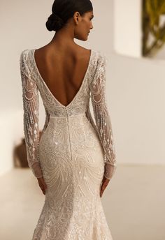 the back of a wedding dress with long sleeves and beading on it, as seen from behind