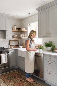 a woman in an apron is standing at the sink