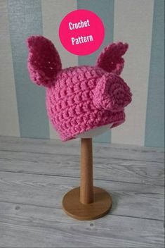 a crocheted hat with ears on top of a wooden stand