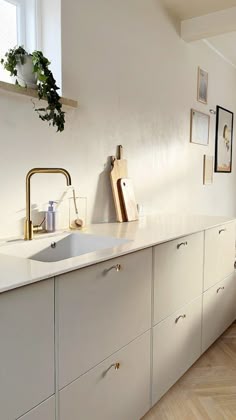 a kitchen with white cabinets and gold faucet pulls on the cabinet doors,