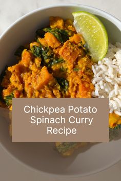 a white bowl filled with chicken and spinach curry on top of rice next to a lime wedge