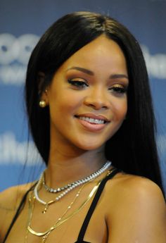 a close up of a person wearing a necklace and pearls on her neck with a microphone in the background