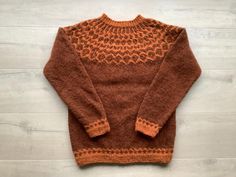 an orange and brown sweater sitting on top of a wooden floor