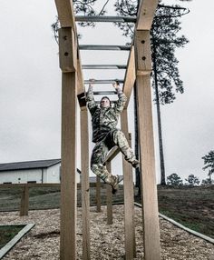 a man in camouflage jumps from a wooden structure into the air