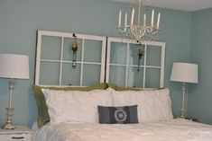 a bedroom with a chandelier hanging over the headboard and two lamps on either side of the bed