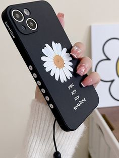 a woman holding up her phone case with a daisy on it