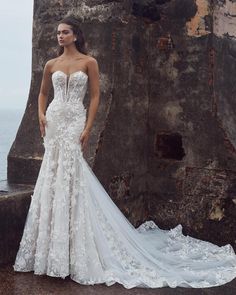 a woman in a wedding dress standing by the ocean