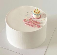 a white cake with pink frosting and sprinkles on it's side