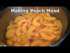 a metal bowl filled with sliced peaches and the words making peach mead on it