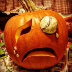 a pumpkin with a baseball in it's mouth and eyes drawn on the inside