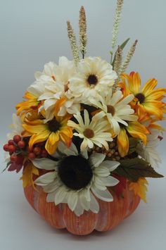 a pumpkin filled with lots of white and yellow flowers