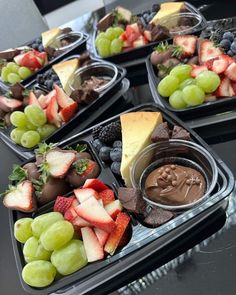 several trays filled with different types of fruit and chocolate covered desserts on top of each other