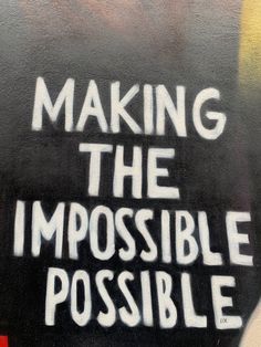 the words making the impossible possible are spray painted on a black and white wall with graffiti