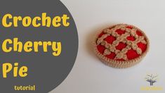 a crochet cherry pie sitting on top of a white table next to a gray circle