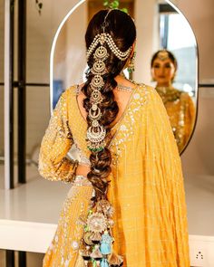 a woman with long hair in a yellow dress is looking at herself in the mirror