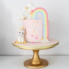 there is a pink cake with a rainbow on it and a unicorn figurine next to it