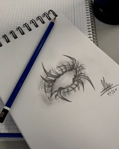 a pencil drawing of an eye on top of a notepad next to a computer mouse