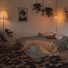 an unmade bed in a room with plants on the wall and pictures above it