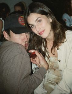 a man and woman sitting next to each other holding wine glasses