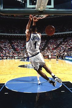 a basketball player dunking the ball in front of an arena full of people watching