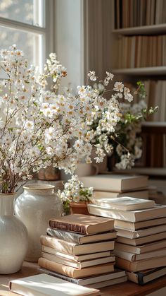 a vase filled with white flowers sitting on top of a wooden table next to books