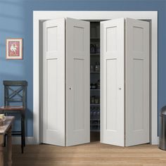 two white doors open in a room with blue walls and wooden floors, one is closed to the other side