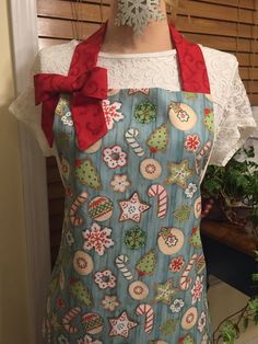 a woman's apron with christmas decorations on it and a red bow around the neck