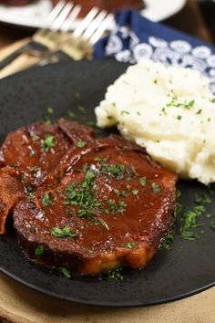 steak, mashed potatoes and gravy on a black plate with a fork