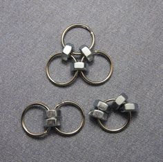 three pieces of metal sitting on top of a gray floor next to two silver rings