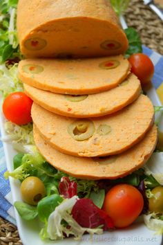 some tortilla bread is stacked on top of a salad with tomatoes, lettuce and olives