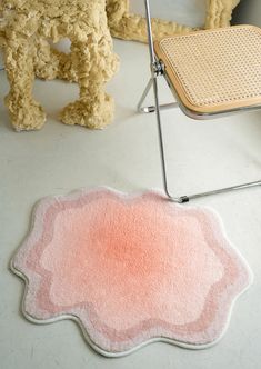 a pink rug sitting on top of a white floor next to a chair and table