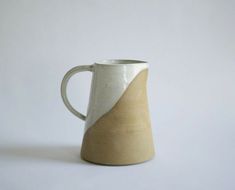 a white and brown coffee mug sitting on top of a table next to a wall