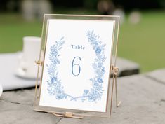 a table number sign sitting on top of a table next to a cup and saucer