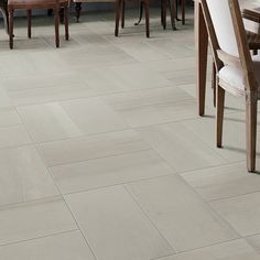 a dining room table and chairs with white tile flooring on the walls behind them