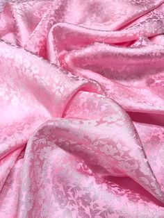 a pink fabric with white flowers and leaves on the bottom, as if it were made from silk