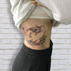 a woman with a fish tattoo on her lower body and bottom half is standing in front of a brick wall