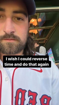 a man with long hair and beard wearing a baseball uniform is looking at the camera