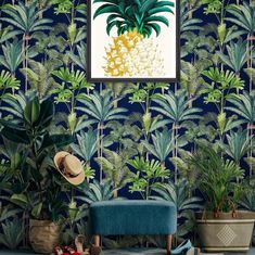 a blue room with palm trees and plants on the wall, in front of a painting