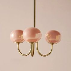 three pink glass balls hang from a brass chandelier