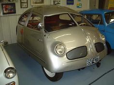 two old cars are parked in a garage