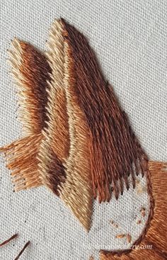 an embroidered piece of cloth with brown and tan colors