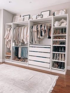 a large white closet with lots of clothes and shoes on the shelves next to a rug